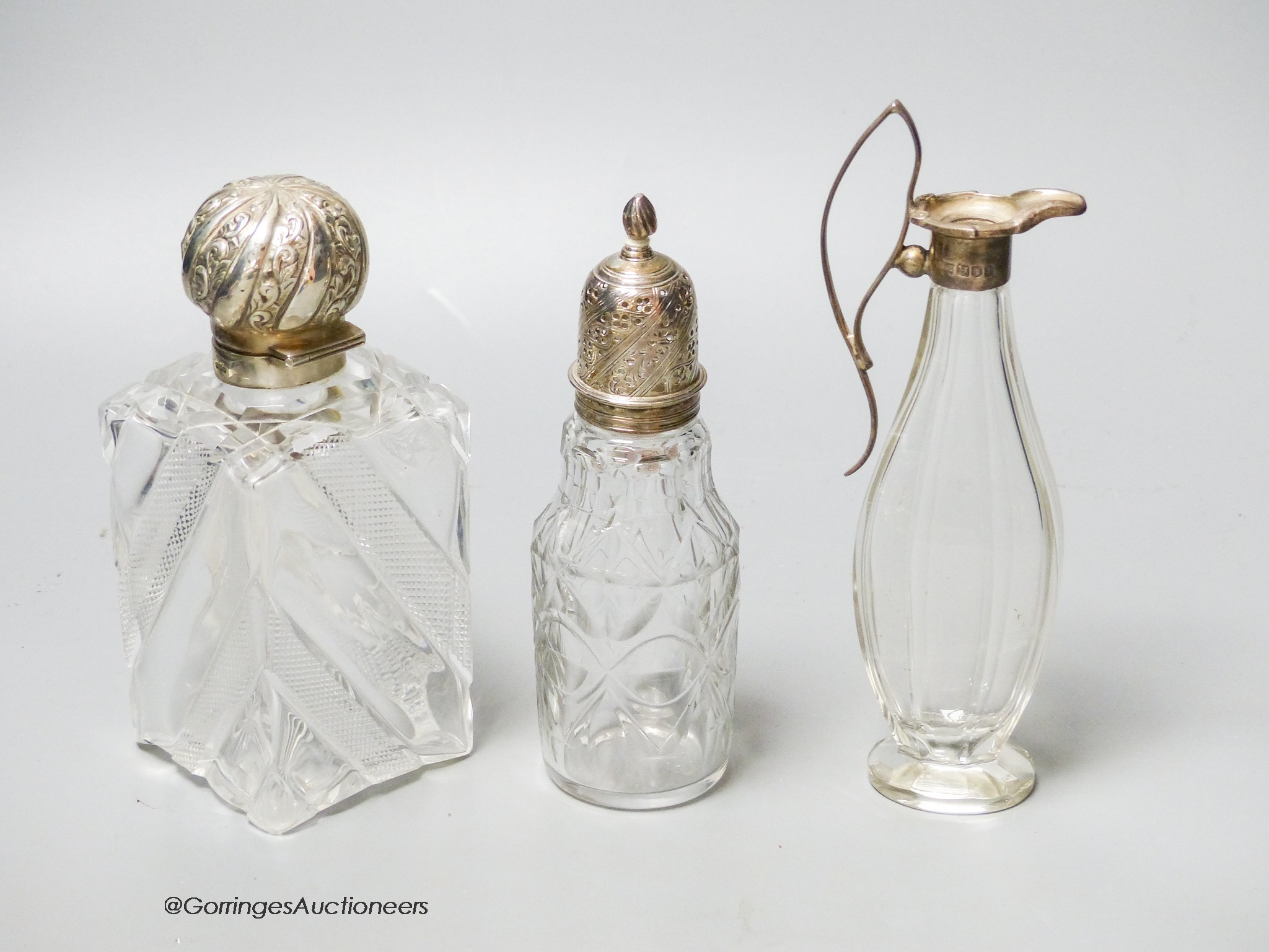 A late Victorian silver topped cut glass scent bottle, London, 1890, 15cm, a later silver mounted glass condiment ewer and silver mounted glass caster.